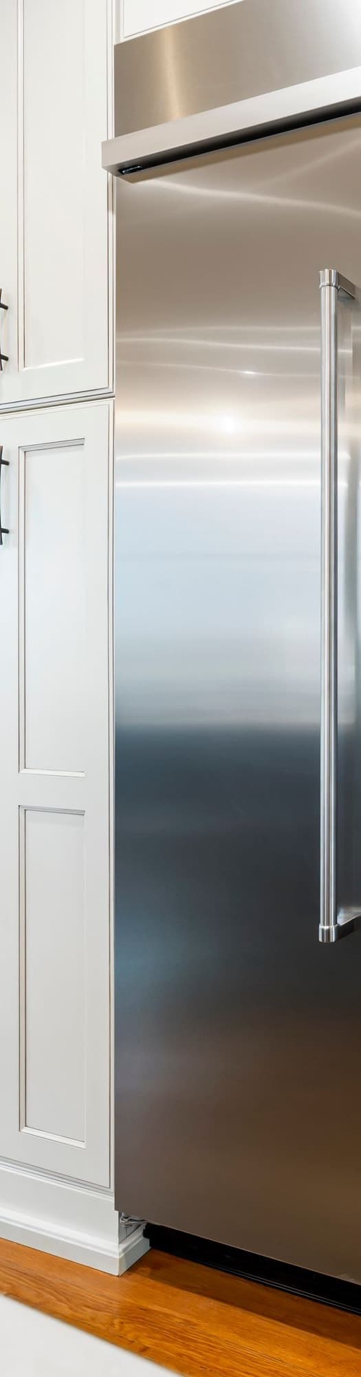 High-end built-in stainless freezer column with a tall door, handle, and top grille